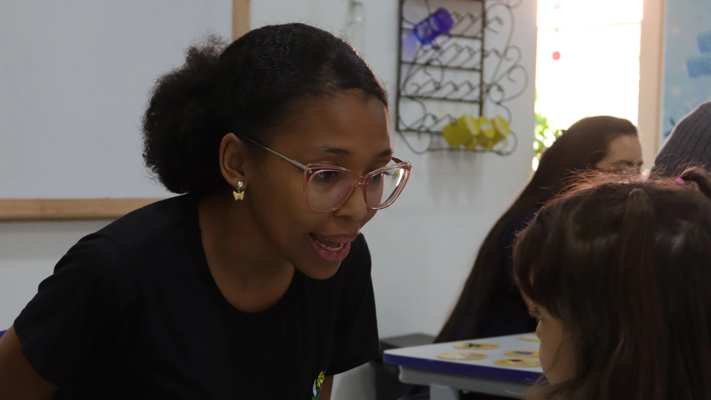 Profissional da APAE sorrindo para uma criança durante um jogo de tabuleiro na sala de atendimento