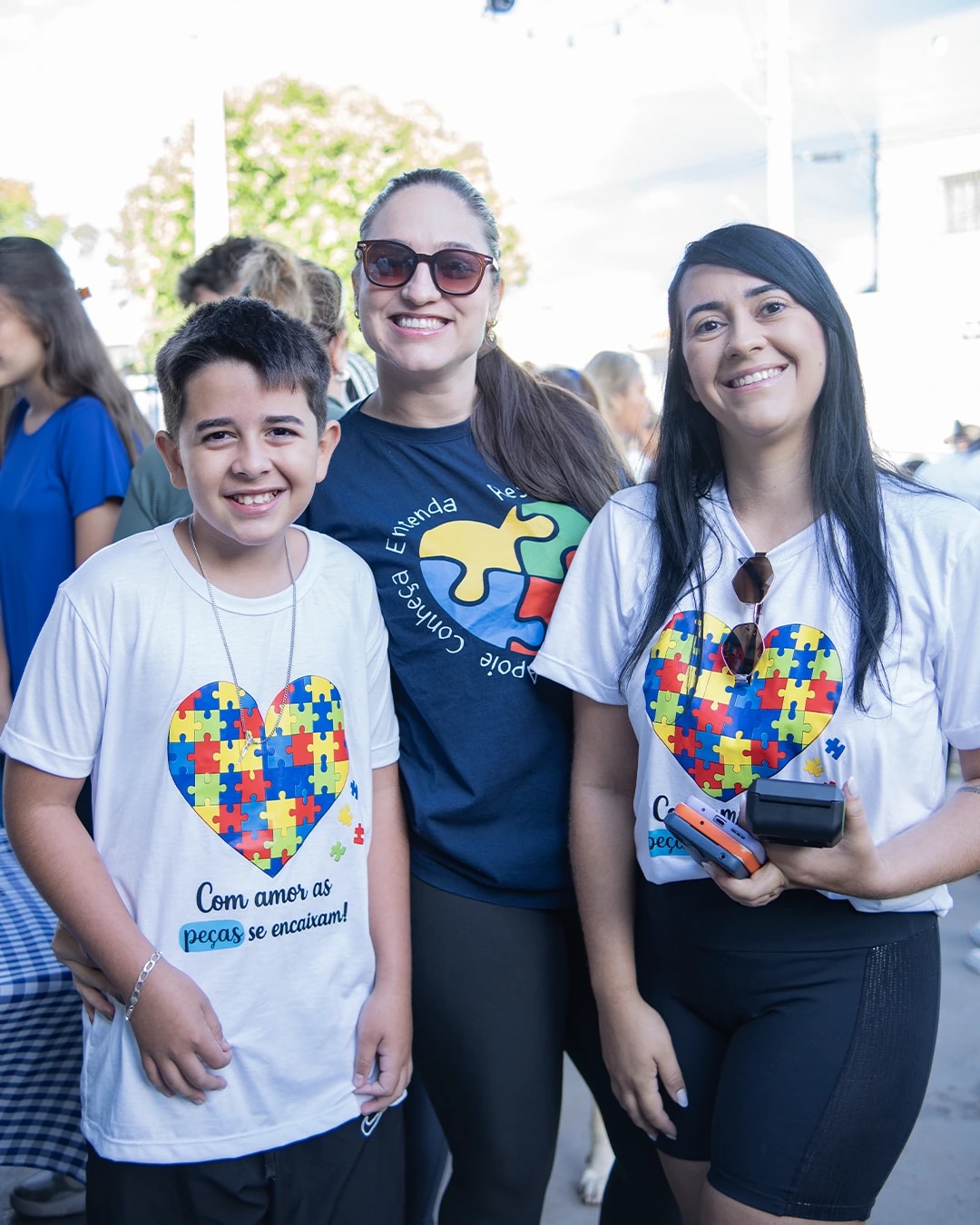 Menino com a camiseta da caminhada posando com duas mulheres da família