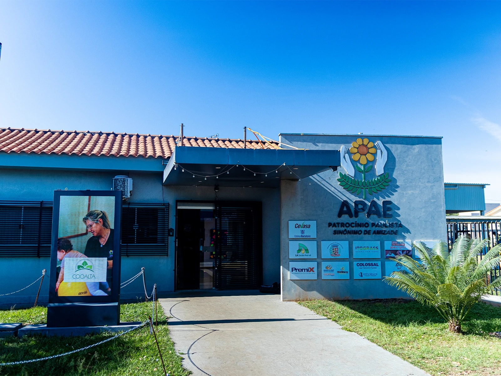 Fachada da sede da APAE em Patrocínio Paulista, com o logo da instituição e os patrocinadores na parede
