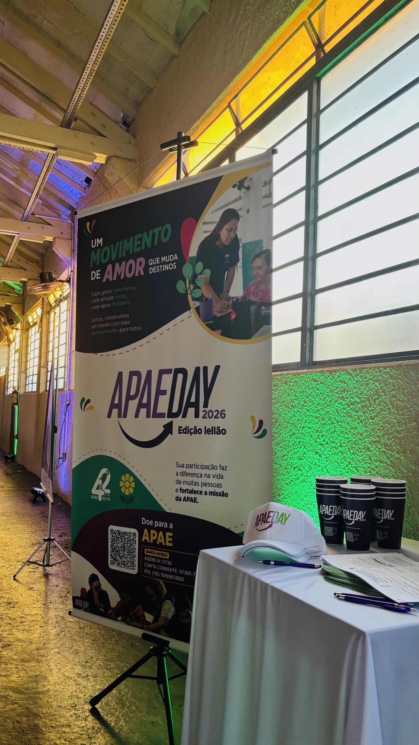 Estande do APAE Day com banner da campanha, bonés e copos personalizados