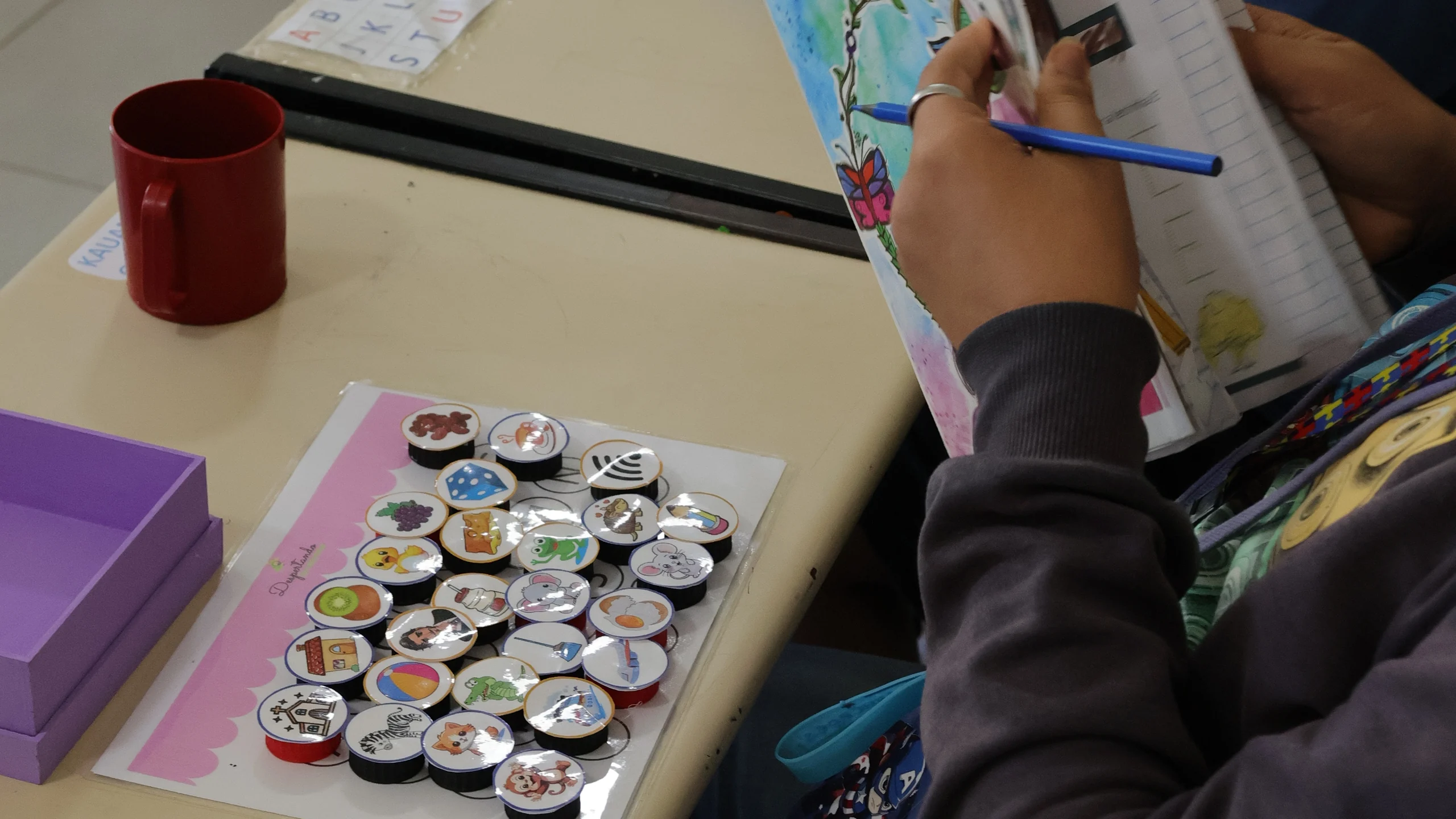Aluno da escola da APAE fazendo atividade em livro na carteira