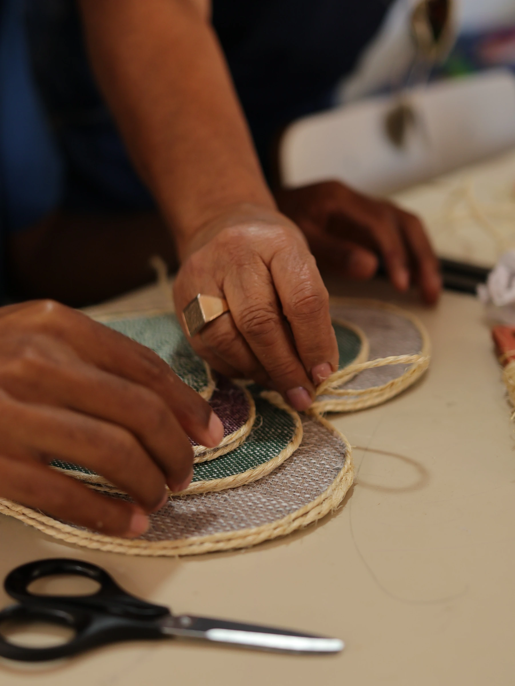 Mãos de um atendido da APAE tecendo uma peça de artesanato com barbante