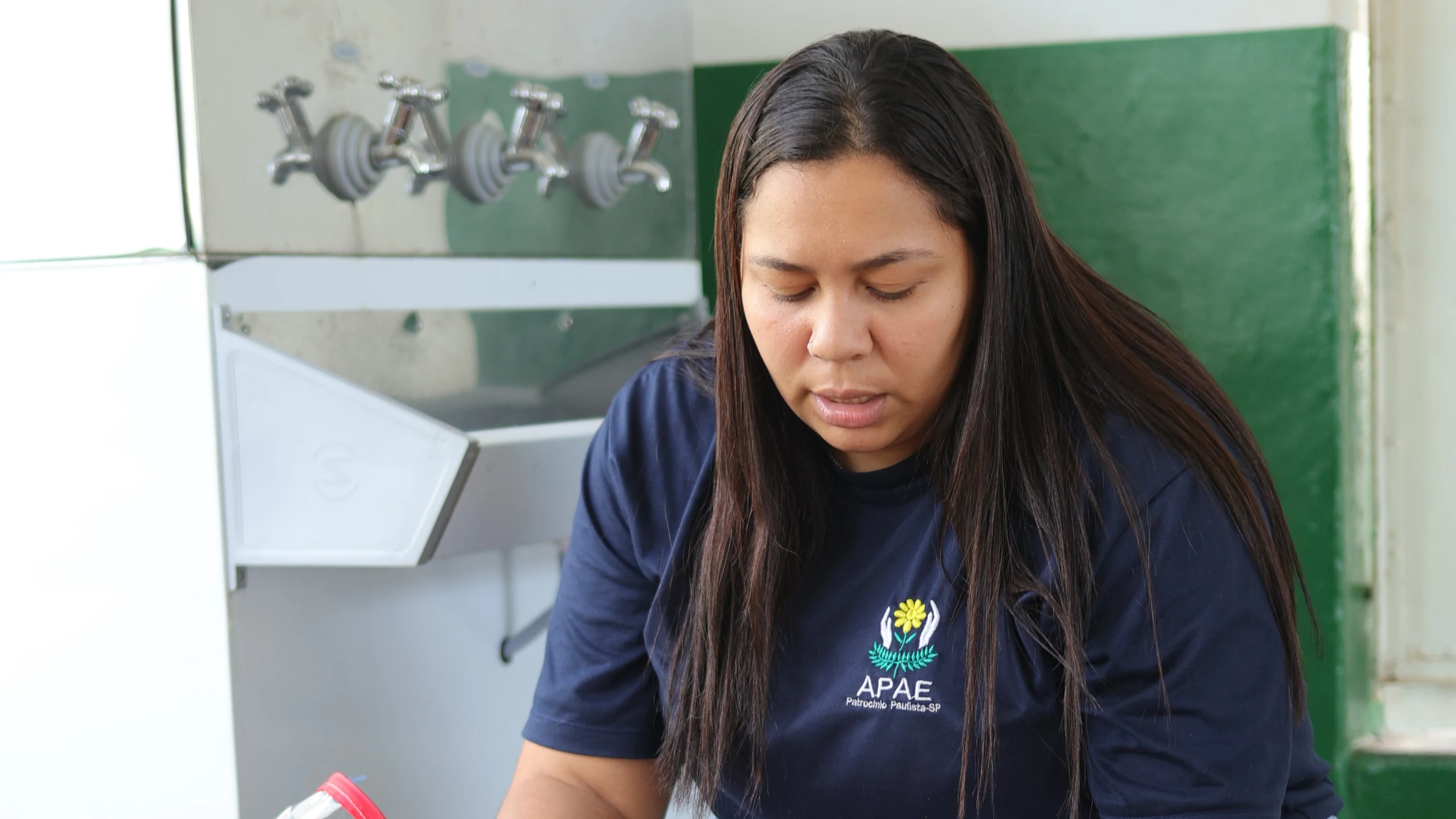 Profissional da APAE, de uniforme, preparando atividade com peças de montar